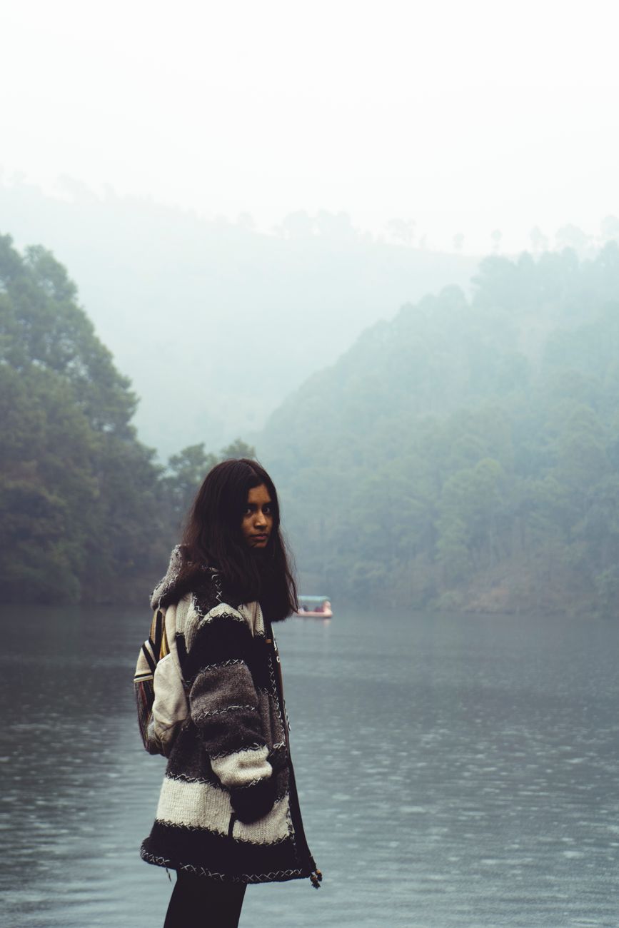 Traveler contemplating nature at edge of mountain lake